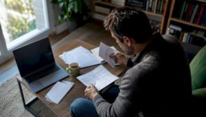 Una persona revisando papeles relacionados con deudas desde la comodidad de su hogar.