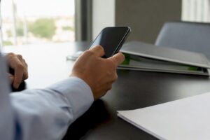 Manos revisando un extracto bancario y un teléfono inteligente