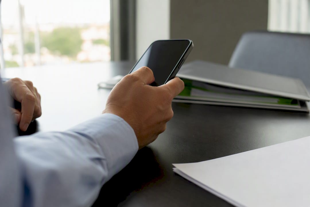 Manos revisando un extracto bancario y un teléfono inteligente