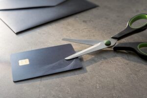Tarjeta anónima al lado de unas tijeras sobre una superficie gris